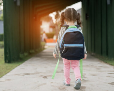 Kid girl pupil walking back to home after learning study school alone with schoolbag,preschool and kindergarten education concept.