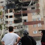 Άνθρωποι μπροστά από κατεστραμμένο κτίριο στην Τεχεράνη