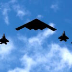 Ένα βομβαρδιστικό B-2 Spirit Stealth της Πολεμικής Αεροπορίας των ΗΠΑ πλαισιώνεται από τέσσερα μαχητικά αεροσκάφη F-22 Raptor