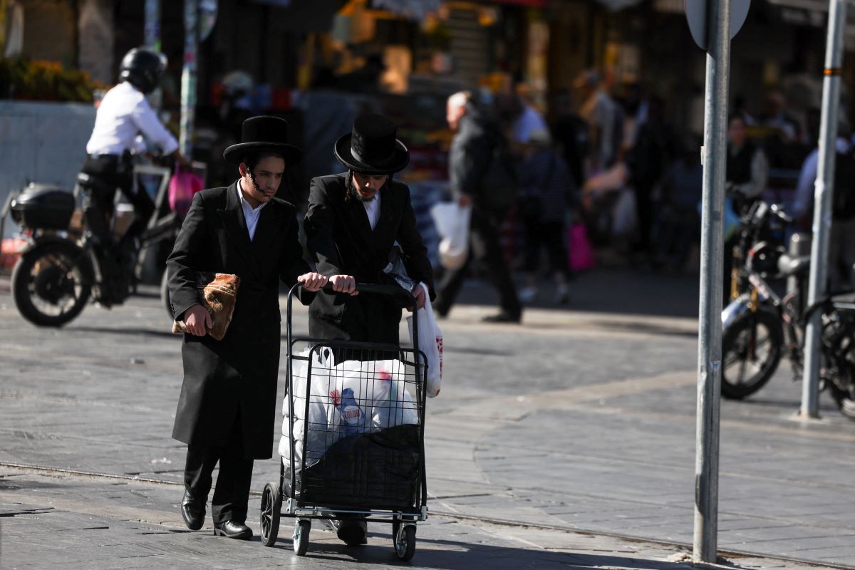 Undenished Jews are pushing a trolley, while Israelis shop on the central market to prepare against Iran's retaliation after Israeli attack