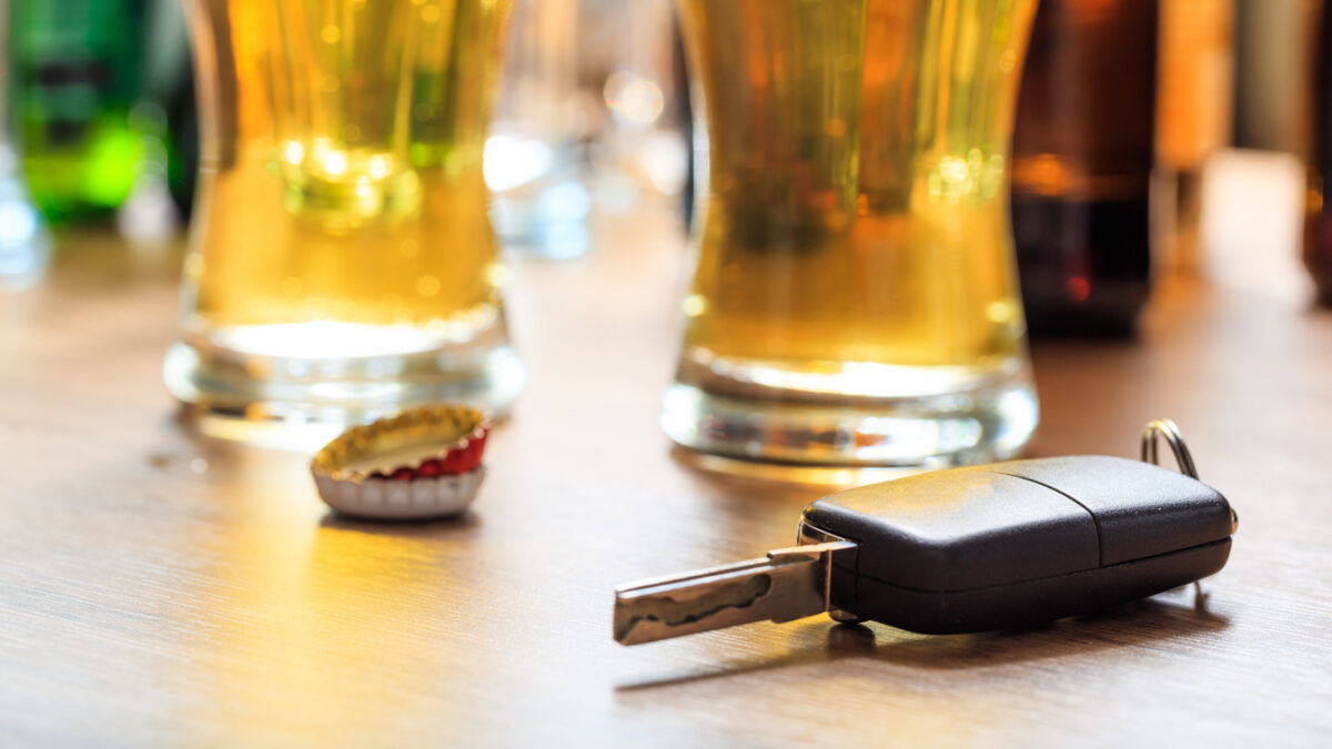 Drinking and driving concept. Car key on a wooden table, pub background