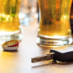 Drinking and driving concept. Car key on a wooden table, pub background