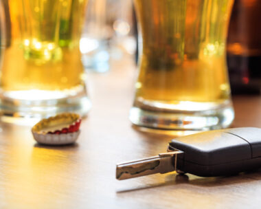 Drinking and driving concept. Car key on a wooden table, pub background