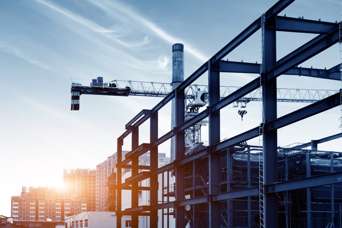 Construction site, silhouettes of construction industry workers on scaffolding against the sunset light