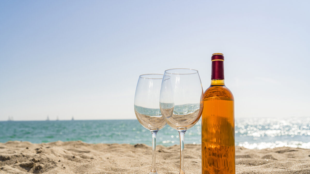 Rose wine bottle and two wineglasses on beach sand. High resolution 42Mp outdoors digital capture taken with SONY A7rII and Zeiss Batis 40mm F2.0 CF lens