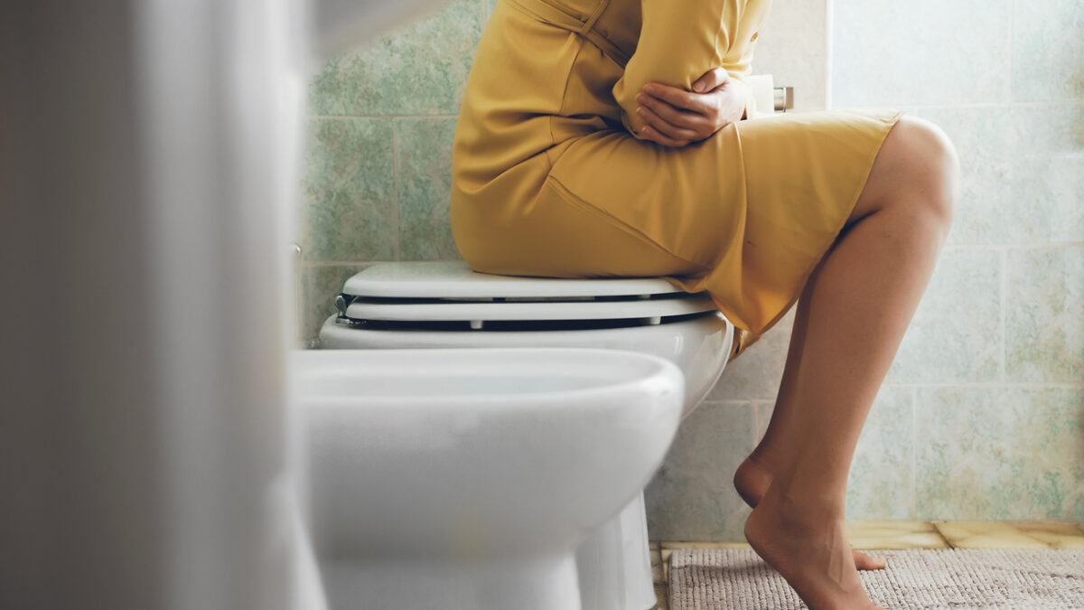 Unrecognizable woman on the toilet with stomach pain