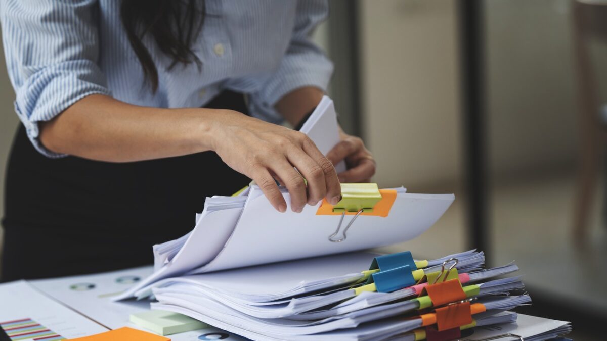 Businesswoman hands working in Stacks of paper files for searching and checking unfinished document achieves on folders papers