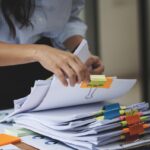 Businesswoman hands working in Stacks of paper files for searching and checking unfinished document achieves on folders papers