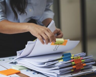 Businesswoman hands working in Stacks of paper files for searching and checking unfinished document achieves on folders papers