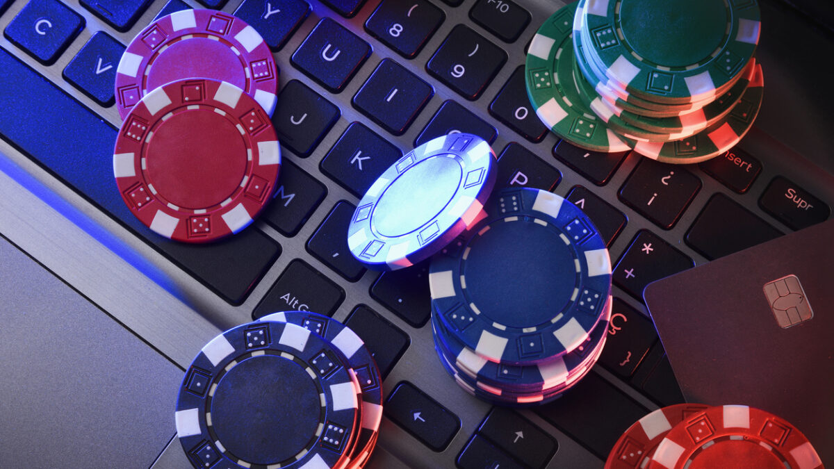 Online game betting concept with chips on laptop keyboard and bank card. Top view.