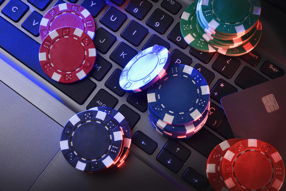 Online game betting concept with chips on laptop keyboard and bank card. Top view.