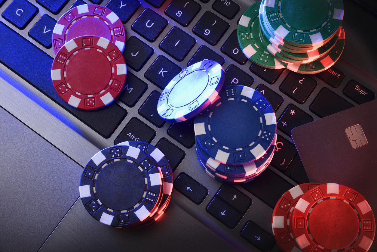 Online game betting concept with chips on laptop keyboard and bank card. Top view.