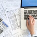 Doing taxes with laptop and tax forms in a house