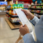 Close-up on a woman shopping at a convenience store and checking her receipt while exiting