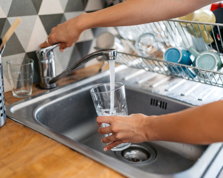 Young woman filling a glass of water in the sink. Close-up.