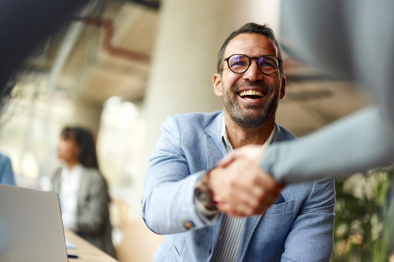 Happy male entrepreneur greeting his colleague while working in the office.
