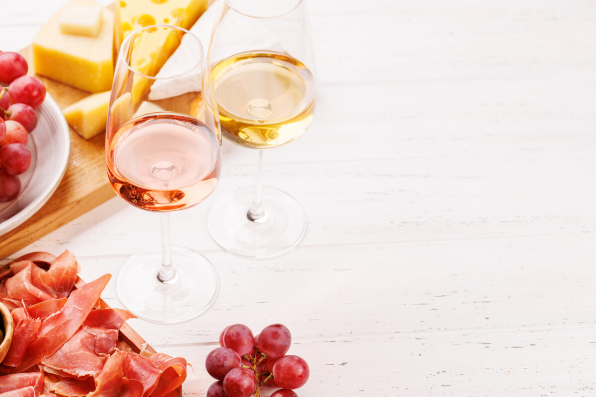 A delectable arrangement of various cheeses, fresh grapes, prosciutto and wine, creating an elegant display for a gourmet dining experience. Perfect for wine and cheese lovers
