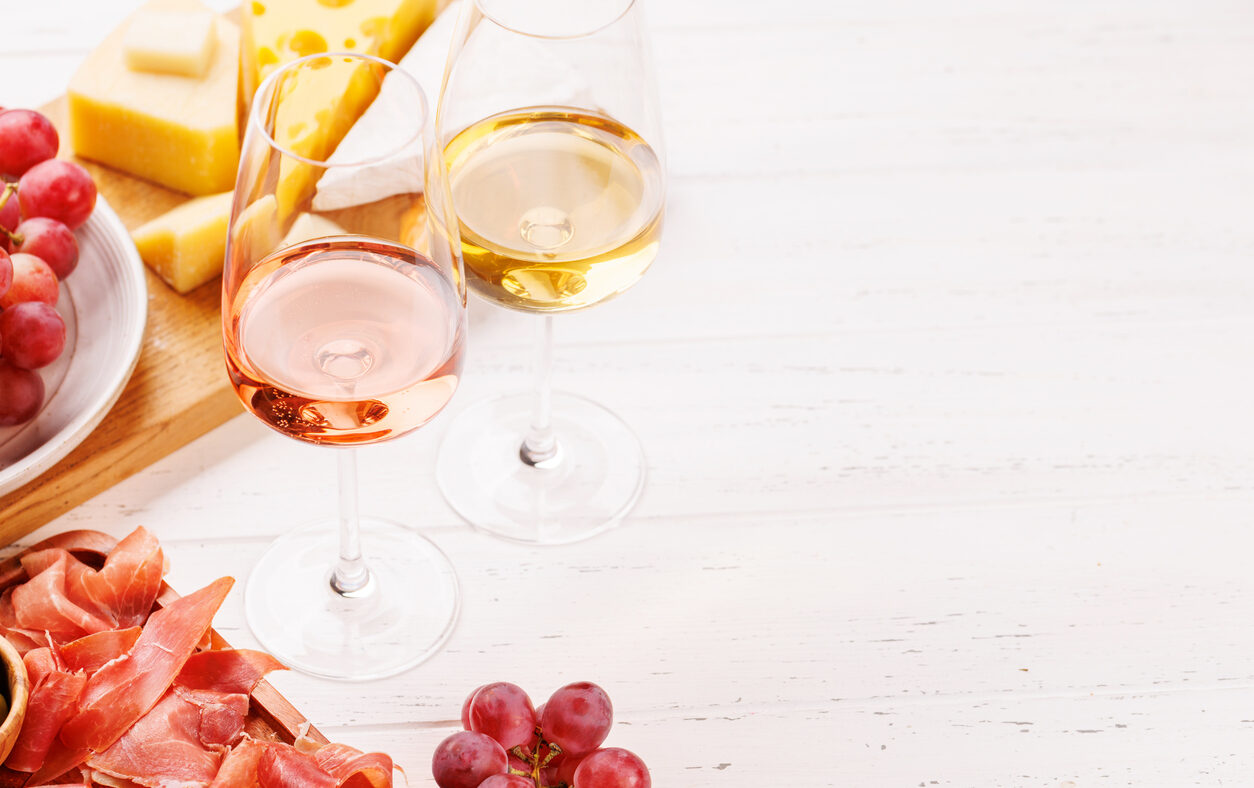 A delectable arrangement of various cheeses, fresh grapes, prosciutto and wine, creating an elegant display for a gourmet dining experience. Perfect for wine and cheese lovers