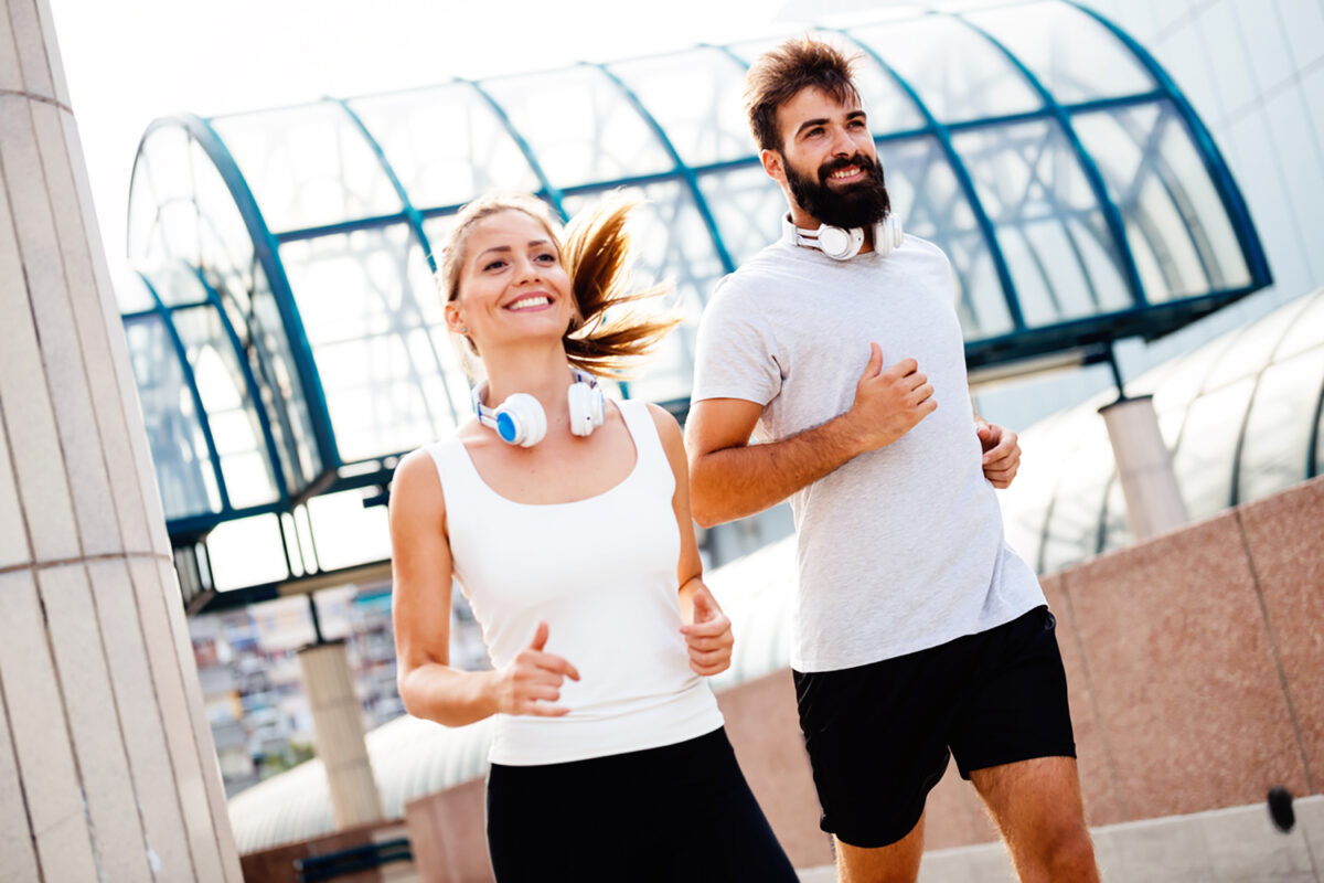 Young fitness couple running together in urban area