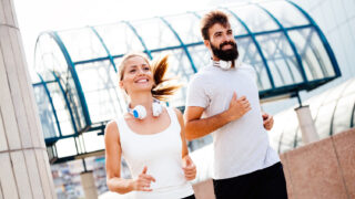 Young fitness couple running together in urban area