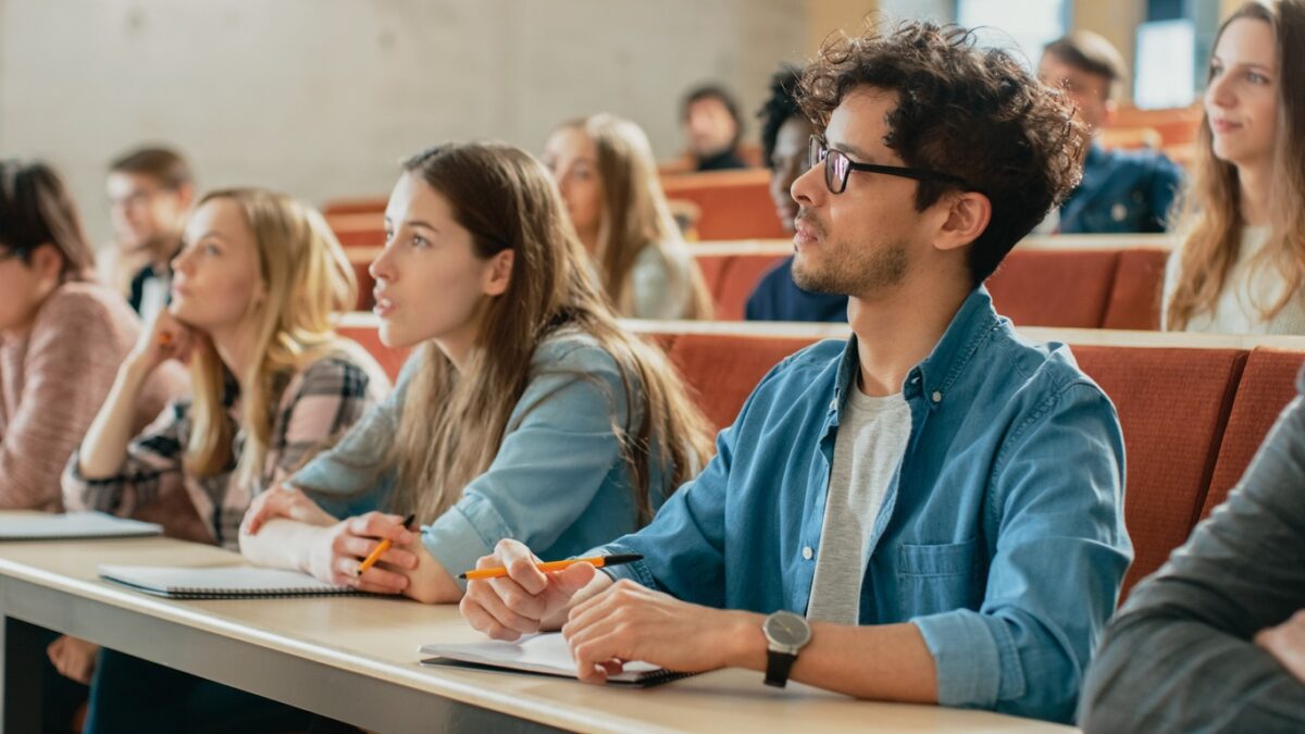 In the Classroom Multi Ethnic Students Listening to a Lecturer and Writing in Notebooks. Smart Young People Study at the College