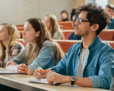 In the Classroom Multi Ethnic Students Listening to a Lecturer and Writing in Notebooks. Smart Young People Study at the College