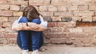 Ένα κορίτσι καθισμένος κρύβει το πρόσωπό του
