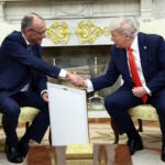 German Chancellor Friedrich Merz holds the framed birth certificate of U.S. President Donald Trump's grandfather as Merz and Trump shake hands during a meeting at the White House in Washington, D.C., U.S., June 5, 2025. REUTERS/Kevin Lamarque