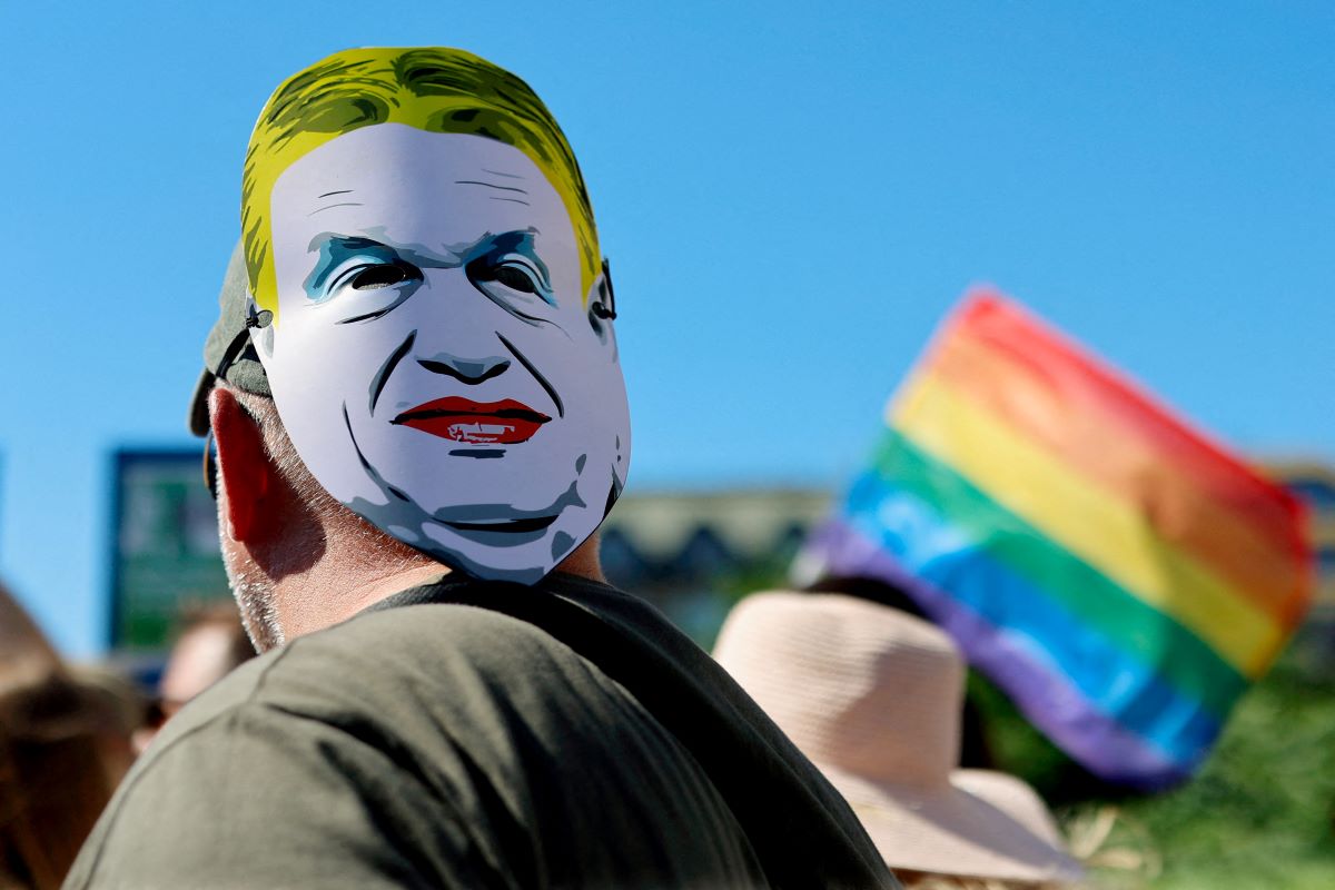 A man participating in Gay Pride, a mask depicting Hungary Prime Minister Victor Orban