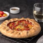 Food photography of galette with tomatoes and ricotta; white wine, seasoning, whole wheat flour; savoury pastry, shortcrust pastry