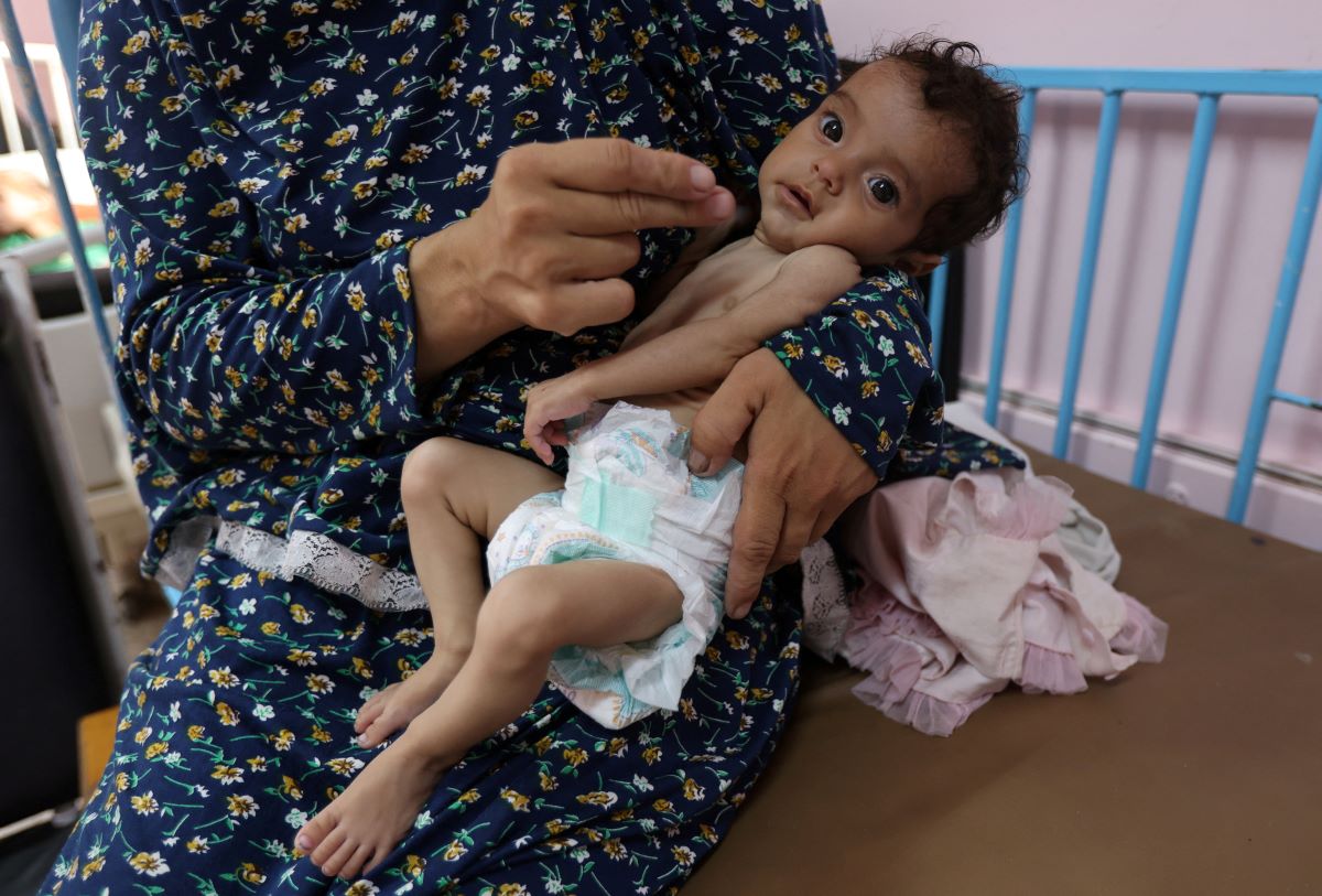 Palestinia holds in her arms her 5 -month -old daughter, Rama Abu Agia