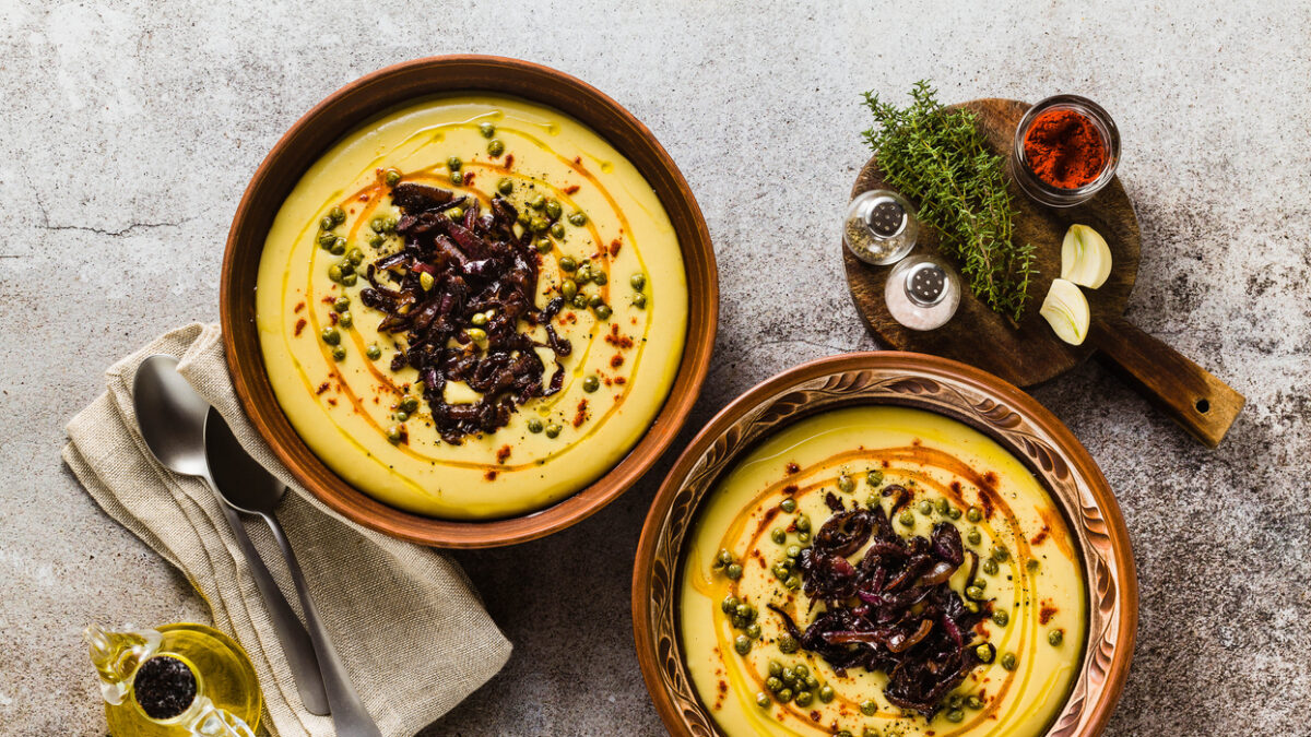 Authentic Greek Fava recipe, Middle Eastern yellow lentil soup with caramelized onions, paprika and capers. vegan healthy food in clay pots on the stone table