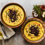 Authentic Greek Fava recipe, Middle Eastern yellow lentil soup with caramelized onions, paprika and capers. vegan healthy food in clay pots on the stone table