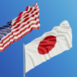 American and Japanese flags are waving with wind over blue sky.