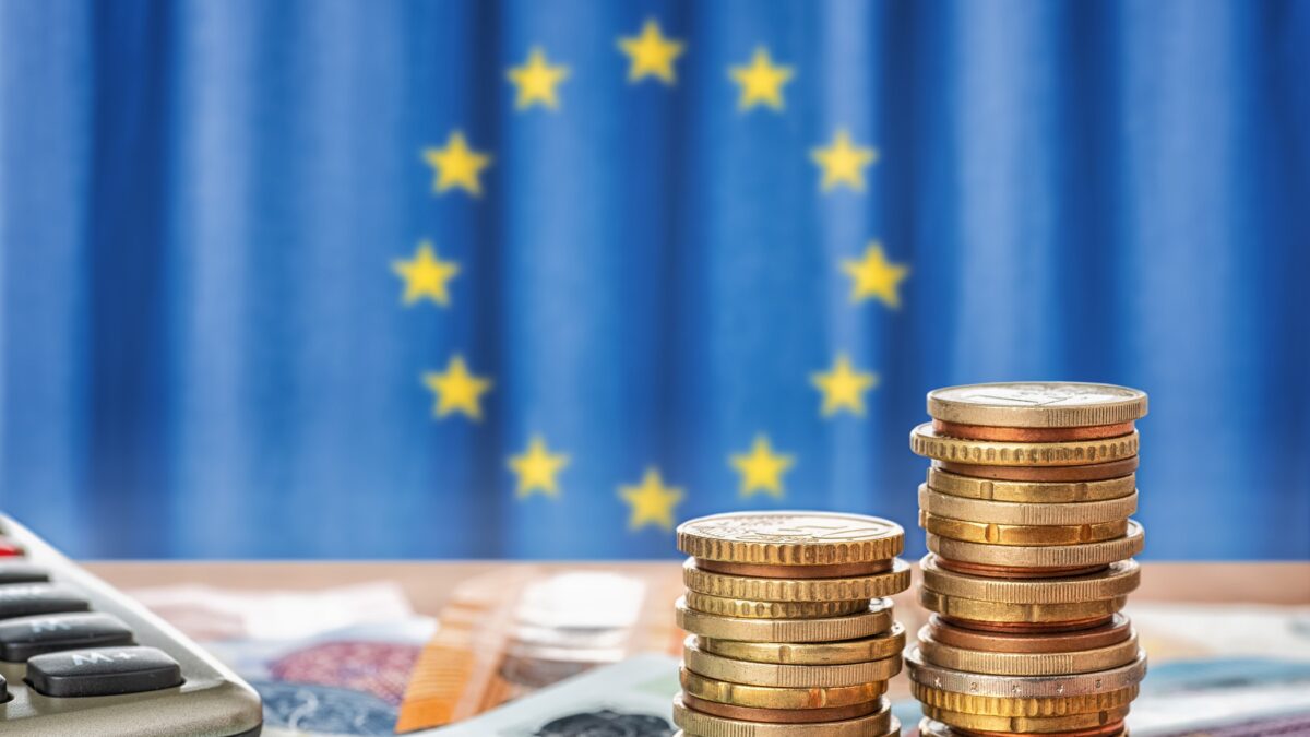 Banknotes and coins in front of the flag of the European Union