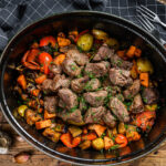 Beef meat stew with potatoes, carrots and herbs. Wooden background