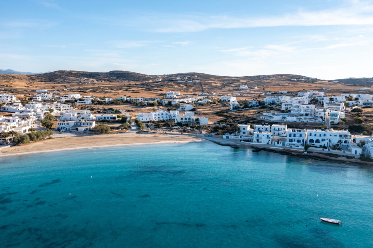 Greece, Koufonisi island, small Cyclades. Aerial drone view. Pano Koufonisi white traditional village buildings, Megali Ammos sandy beach. Calm turquise sea water, clear blue sky background.
