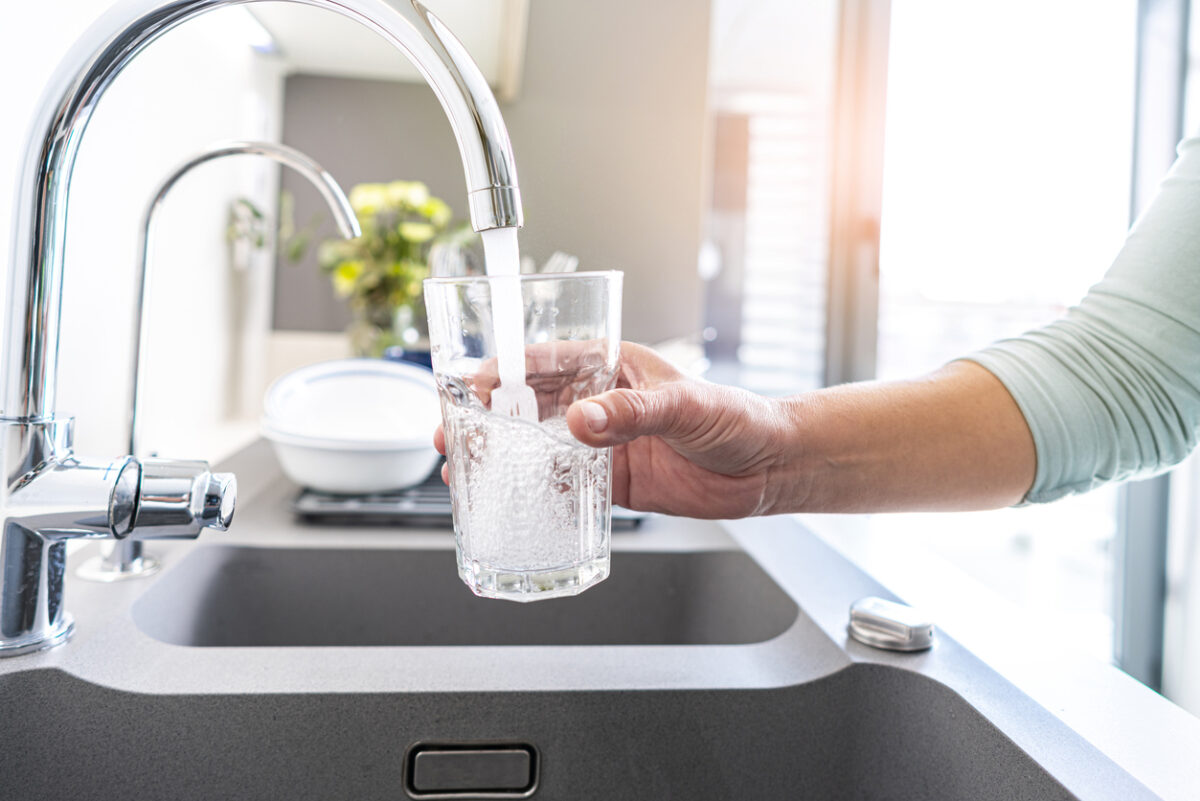 Close up of a woman hand filling a glass of water directly from the tap. High resolution 42Mp indoors digital capture taken with SONY A7rII and Zeiss Batis 25mm F2.0 lens