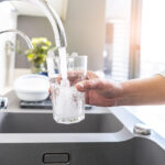 Close up of a woman hand filling a glass of water directly from the tap. High resolution 42Mp indoors digital capture taken with SONY A7rII and Zeiss Batis 25mm F2.0 lens