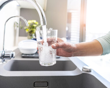 Close up of a woman hand filling a glass of water directly from the tap. High resolution 42Mp indoors digital capture taken with SONY A7rII and Zeiss Batis 25mm F2.0 lens