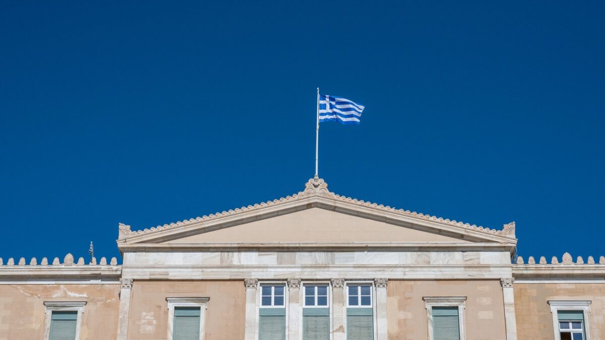 A low angle shot of the Hellenic Parliament and a Greek flag on its rooftop, Athens, Greece