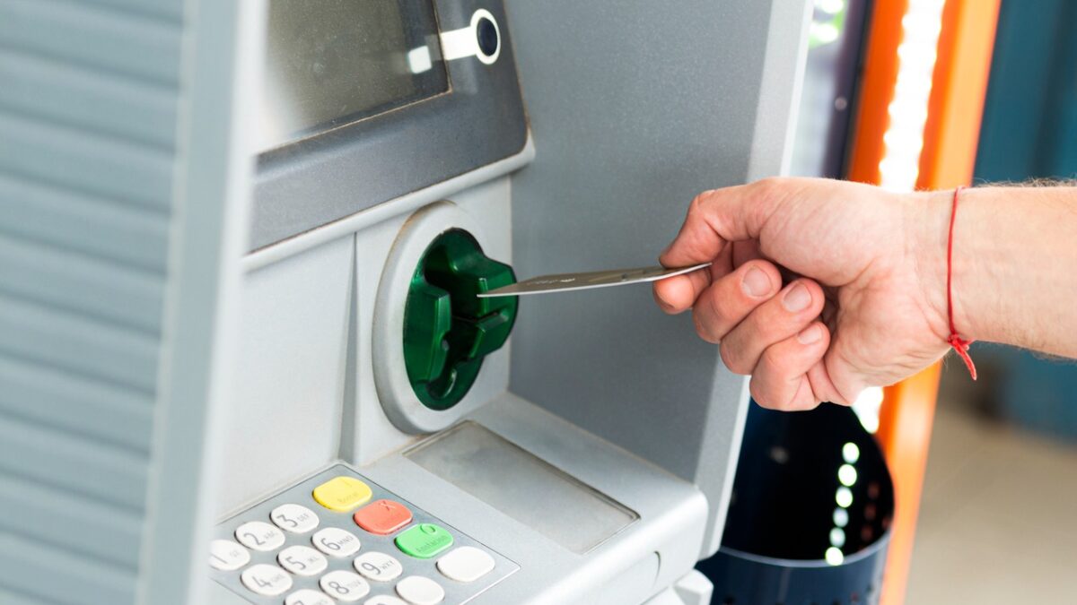 Human hand inserting a credit card into an ATM