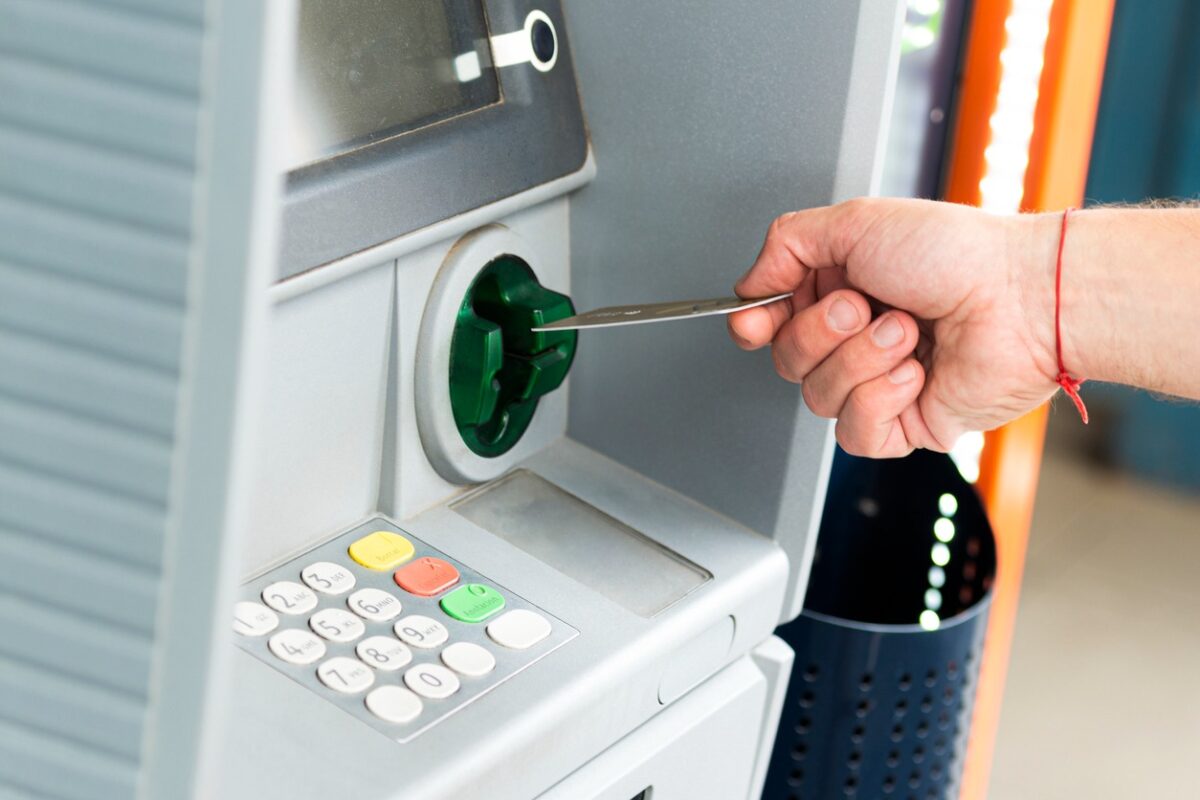 Human hand inserting a credit card into an ATM
