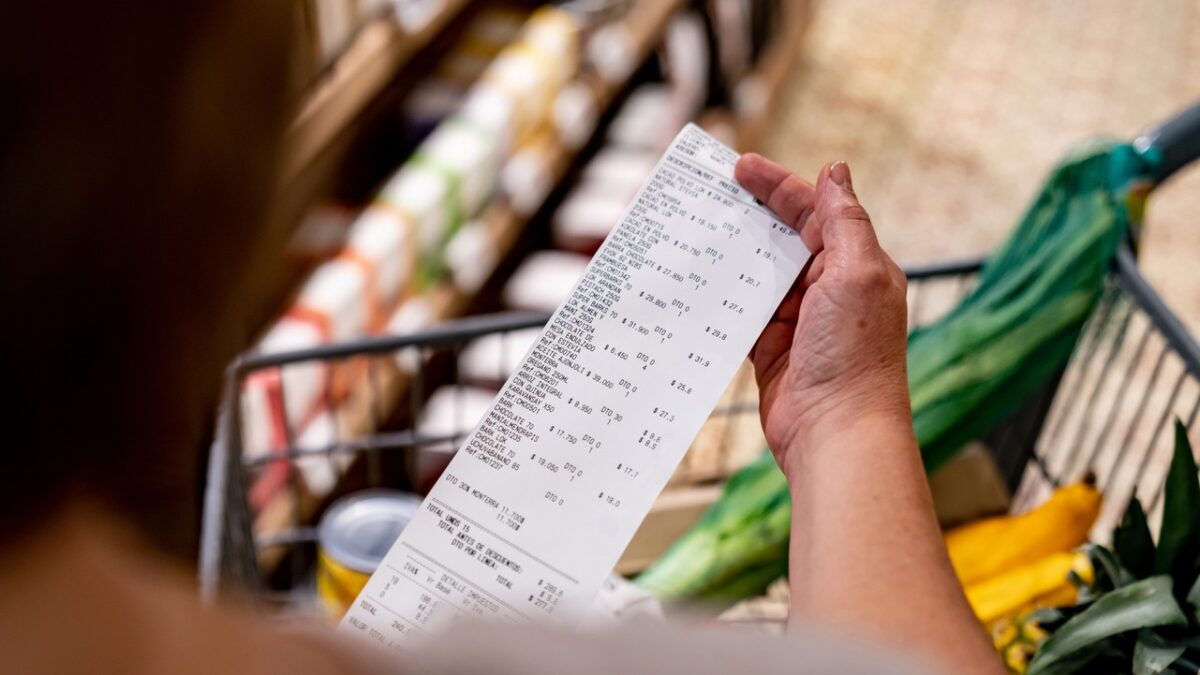 Close-up on a woman looking at a receipt after shopping at the supermarket - cost of living concepts