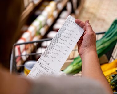 Close-up on a woman looking at a receipt after shopping at the supermarket - cost of living concepts