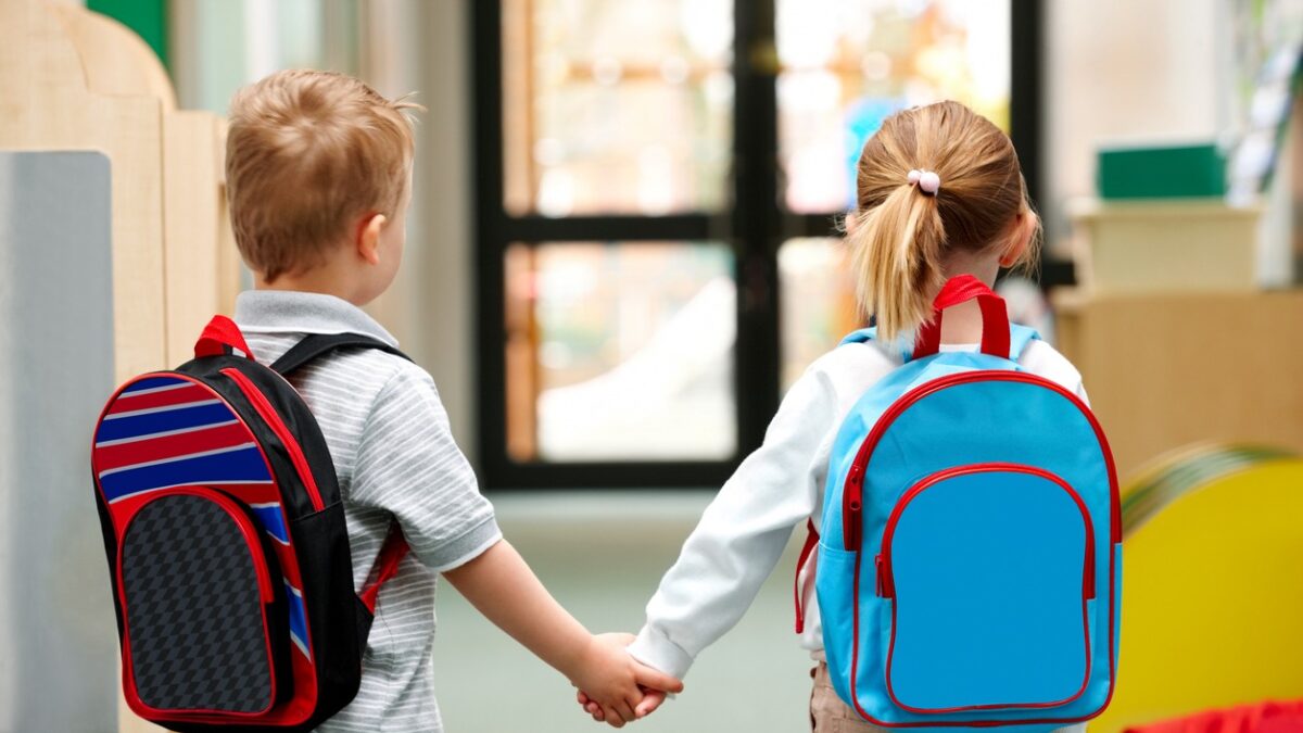 Two cute little children walking to school - Rear view