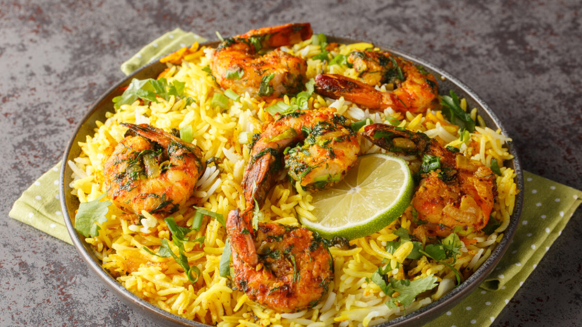 Popular Iranian seafood pilaf Meygoo Polo with herbs and prawns closeup on the plate on the table