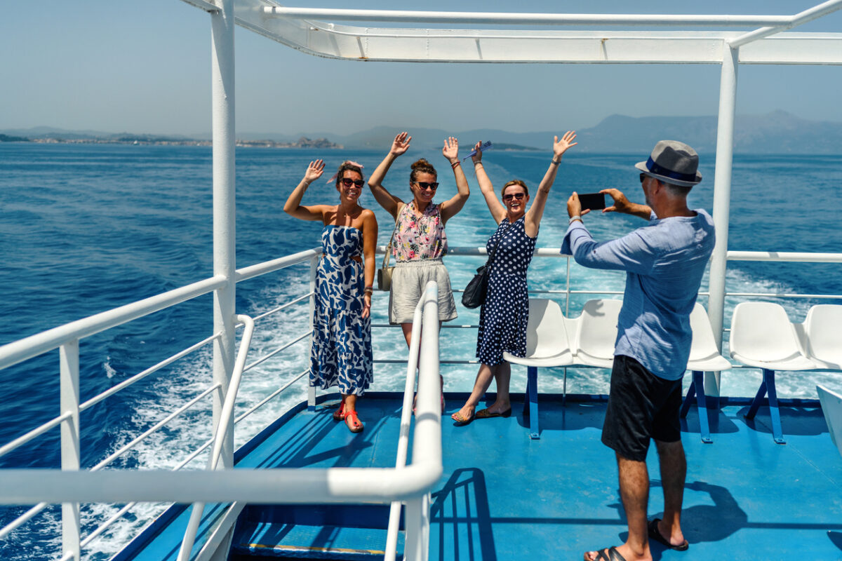 Group of friends on the ferry boat deck on a sunny day traveling on vacation
