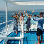 Group of friends on the ferry boat deck on a sunny day traveling on vacation