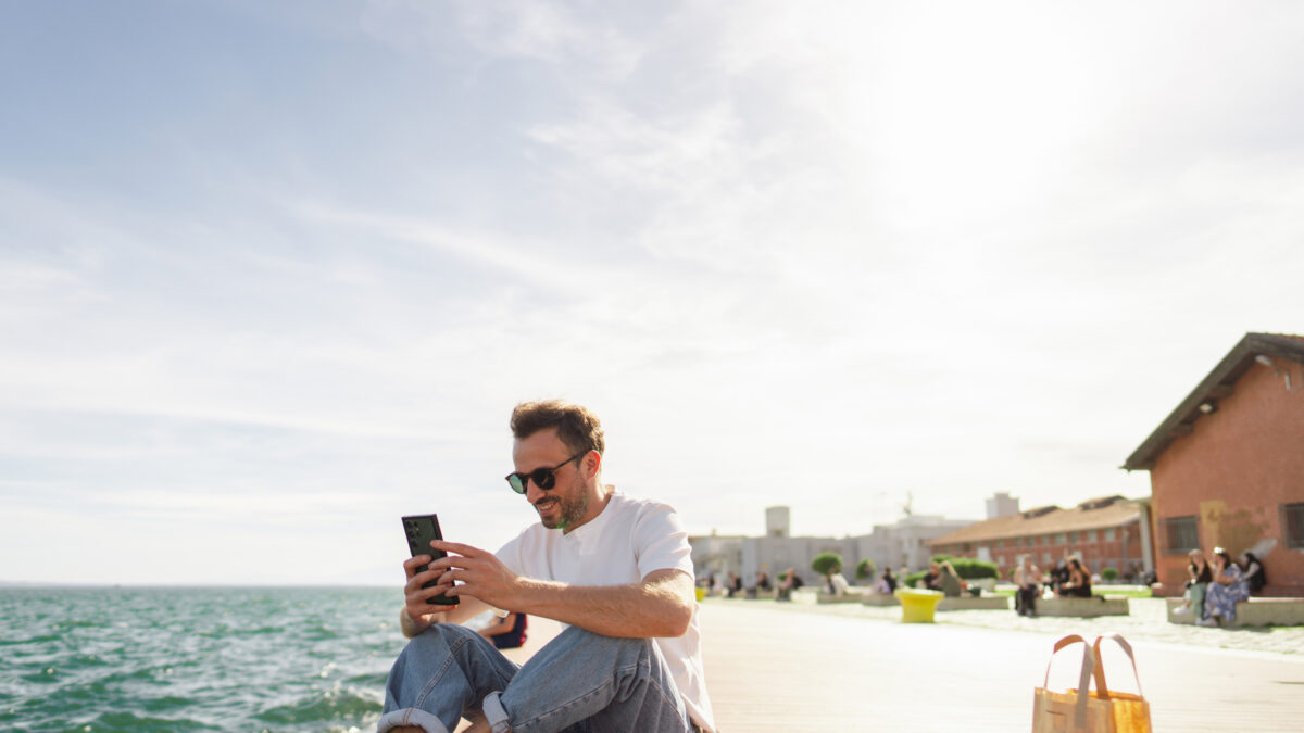 Young man taking a break during the day, sitting on a pier and enjoying springtime sun